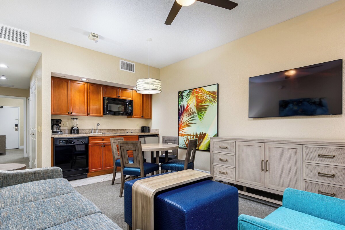 A compact living space with a kitchenette, a dining area, and a seating area with a sofa and chairs.