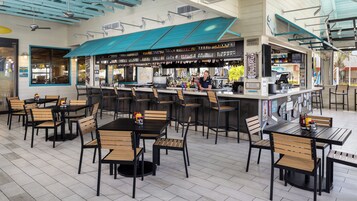 Een restaurant met een bar, verschillende zithoeken en een ruim assortiment aan eten en drinken.