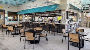 A restaurant with a bar area, multiple seating arrangements, and a variety of food and drink items displayed.