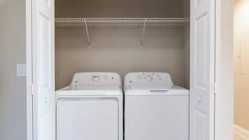 A laundry room with two front-loading washing machines and a metal drying rack above.