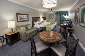 A hotel room with a bed, a sofa, a dining table with chairs, a lamp, and a ceiling fan. - Holiday Inn Club Vacations at Orange Lake Resort by IHG (Kissimmee)