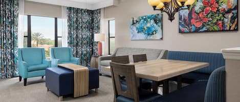 A modern living room with a sofa, armchairs, a dining table, and a ceiling fan.