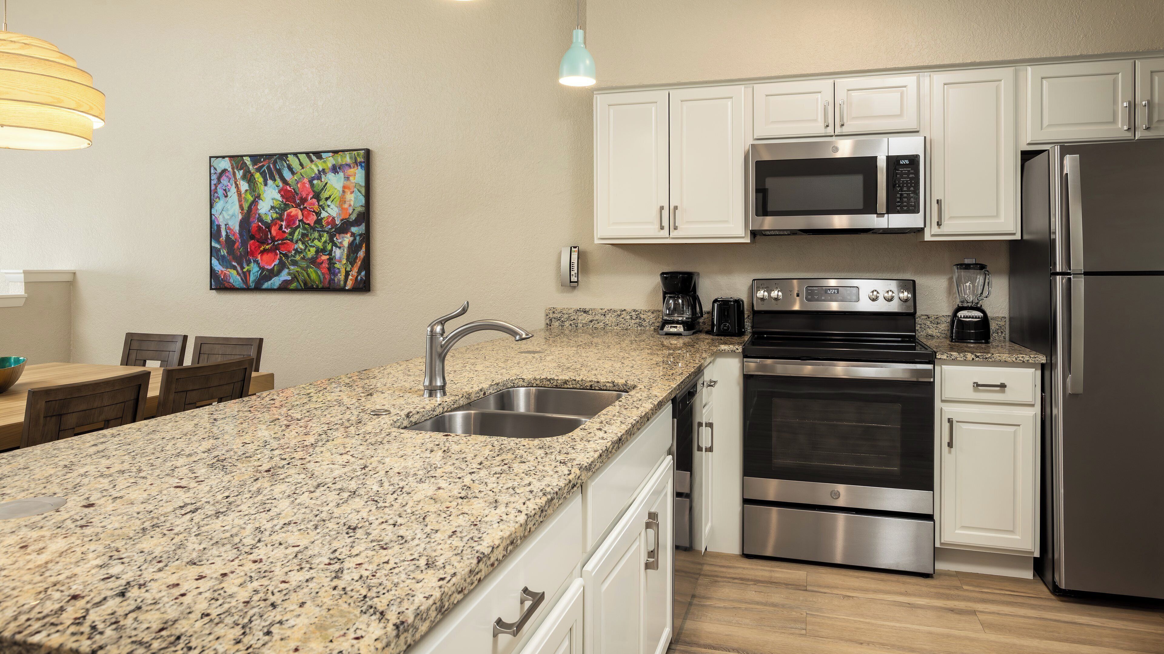 A modern kitchen with granite countertops, stainless steel appliances, and white cabinetry.