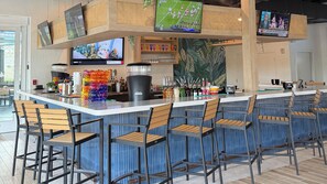 A bar area with multiple seating options, a counter with various beverages, and screens displaying sports events. - Holiday Inn Club Vacations at Orange Lake Resort by IHG (Kissimmee)