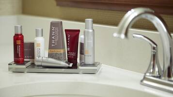 A bathroom sink with various Thann skincare products arranged on a tray.