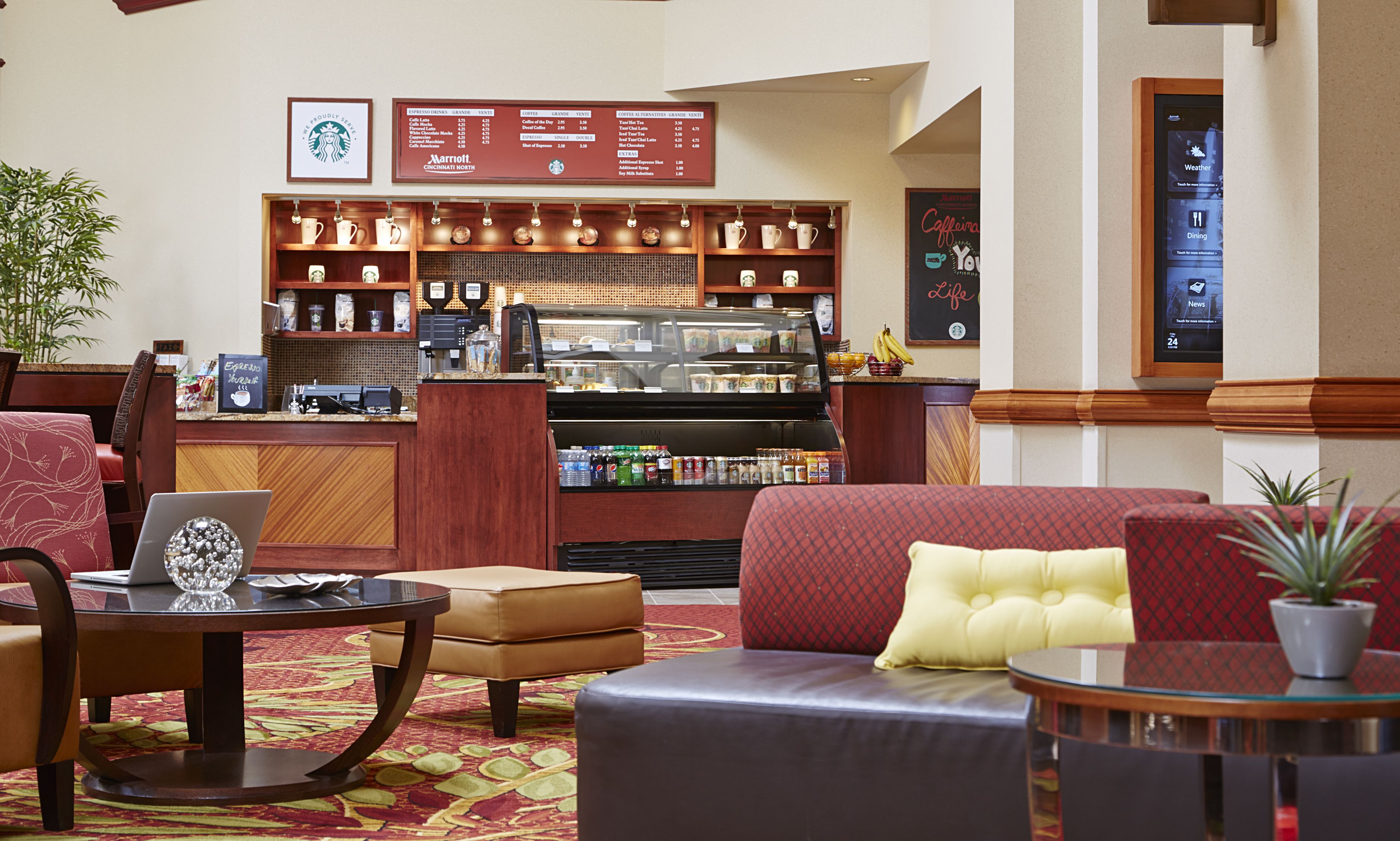 Un hall d’hôtel avec des sièges, un bar à café et un panneau affichant le menu.