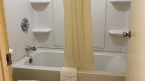 A bathroom with a bathtub, toilet, and a shower curtain.