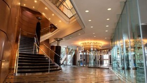 A modern hotel lobby with a grand staircase, a revolving door, and a glass wall offering a view of the interior. - Hilton Toronto/Markham Suites Conference Centre & Spa (Markham)