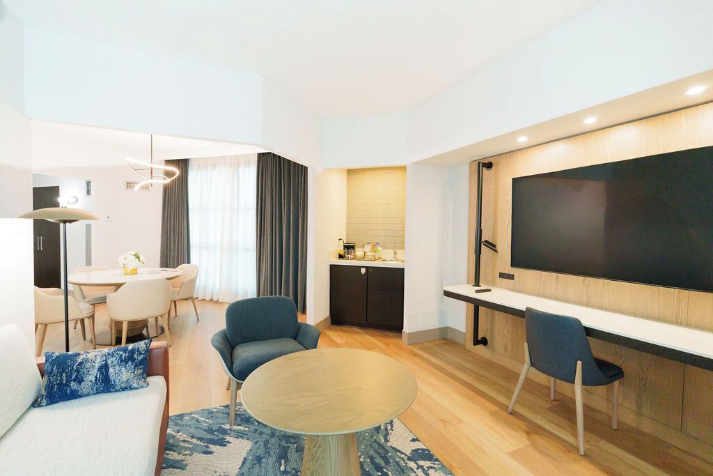 A modern living room with a flat-screen TV, a dining area, and a kitchen.