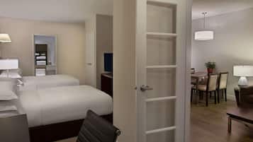 Ett hotellrum med en säng, ett skrivbord, en stol, ett matbord och en krukväxt.