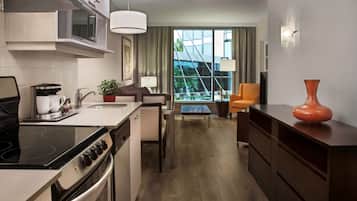 A modern kitchen with a stove, oven, and microwave. There is a dining area with a table and chairs, and a large window offering a view of the outside.