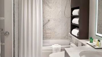 A marble bathroom with a bathtub, a shower, a vanity with a mirror, and a towel rack.