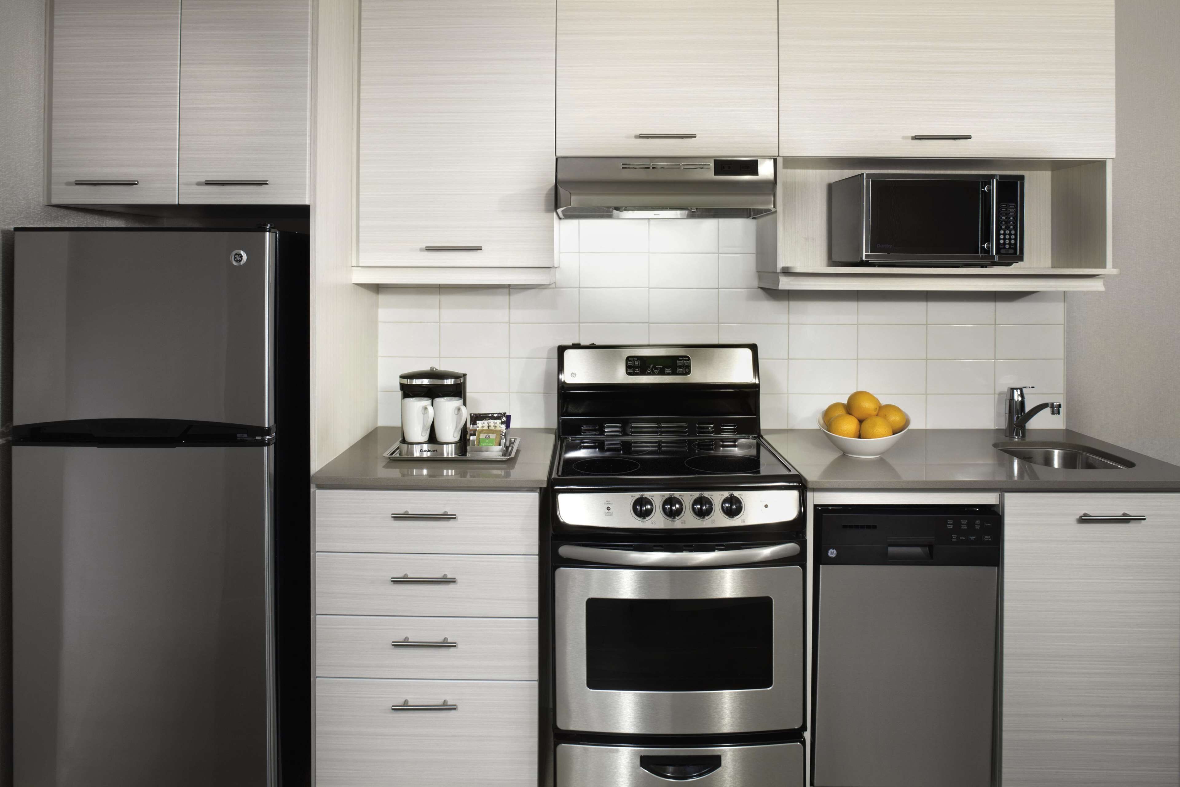 A modern kitchen with stainless steel appliances, including a refrigerator, stove, oven, and dishwasher.