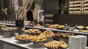 A buffet with various pastries and breads, including croissants and baguettes, arranged on a counter with plates and serving utensils. - Hilton Toronto/Markham Suites Conference Centre & Spa (Markham)