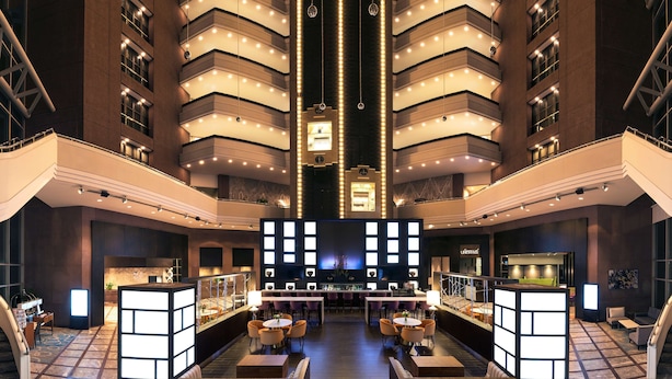 A spacious lobby with a central reception desk, multiple seating areas, and a modern architectural design with a high ceiling and illuminated vertical lines. - Hilton Toronto/Markham Suites Conference Centre & Spa (Markham)