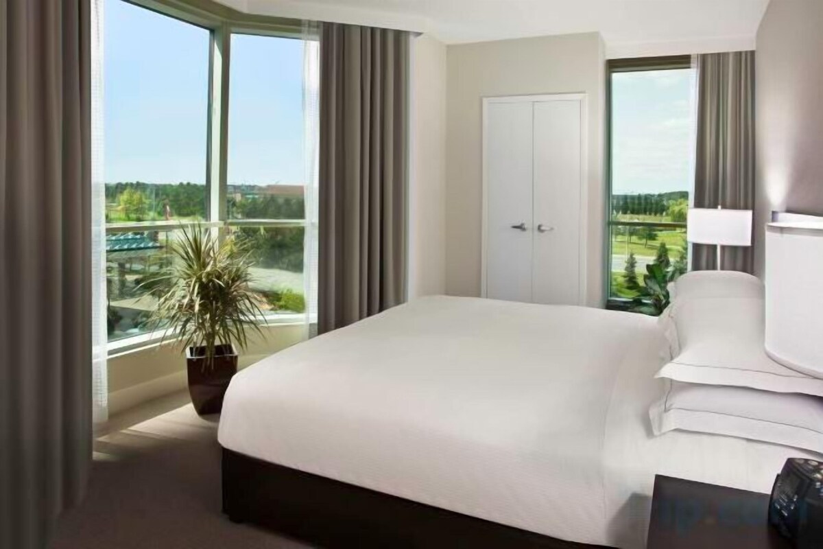Ein Hotelzimmer mit einem großen Bett, einer Topfpflanze und Blick auf einen Golfplatz.