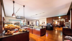 Een ruime hotellobby met een houten receptiebalie, een buffetgedeelte met diverse gerechten, en een zithoek met tafels en stoelen.