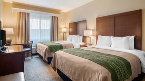 A hotel room with two beds, a desk, a chair, and a TV.