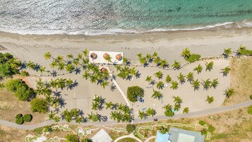 En la playa, arena negra, sillas reclinables de playa, vóleibol de playa
