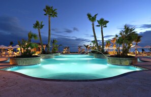 A swimming pool with palm trees and lounge chairs, surrounded by a sandy area. - Hilton Ponce Golf & Casino Resort (Ponce)