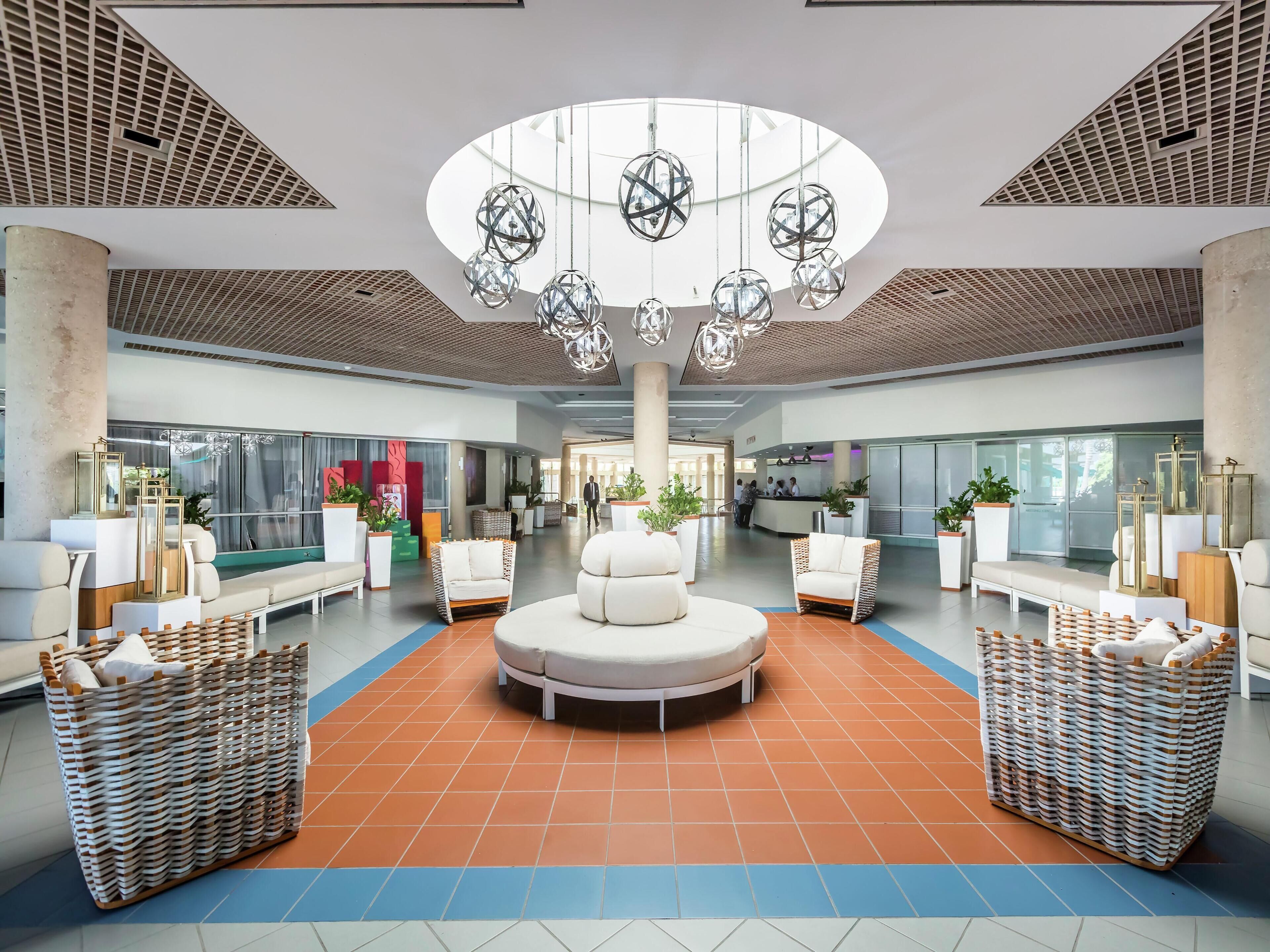 A spacious lobby with a central seating area, a reception desk, and large windows.