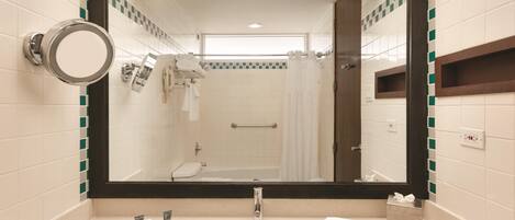 A bathroom with a large mirror, a sink, a towel rack, and a shower area.