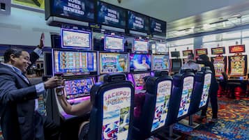 A casino with multiple slot machines and a person playing one.