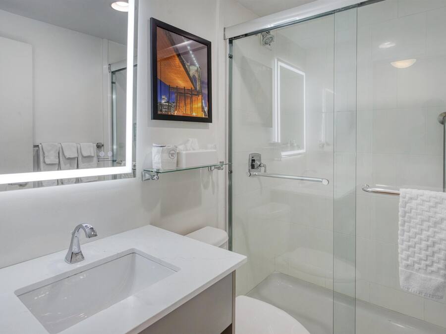A modern bathroom with a glass shower enclosure, a white sink, and a large mirror.
