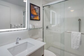 A modern bathroom with a glass shower enclosure, a white sink, and a large mirror. - Best Western Gregory Hotel (Brooklyn)