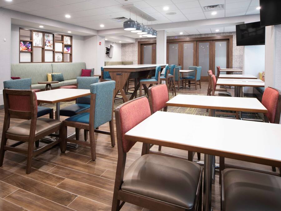 Un restaurant avec des tables et des chaises en bois, un canapé et un téléviseur fixé au mur.