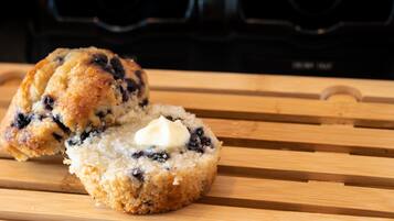 A muffin with a dollop of butter on a wooden surface.