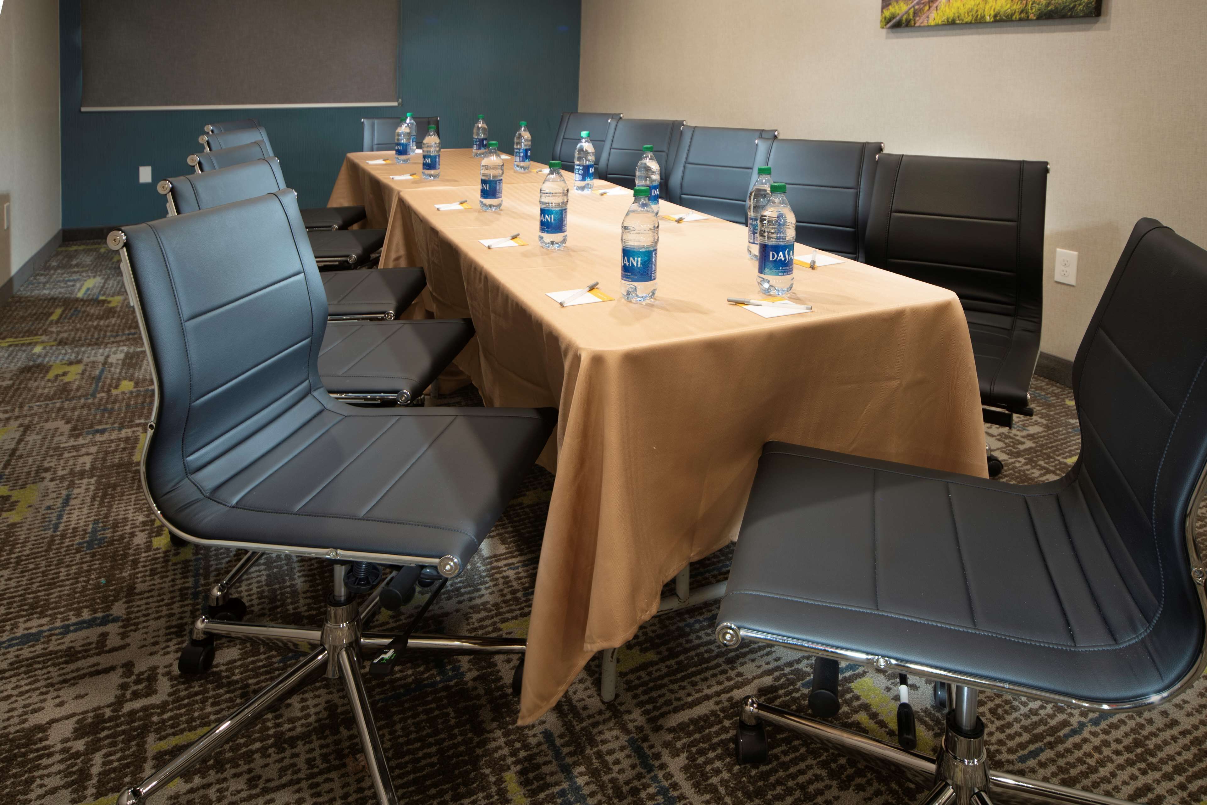 Une salle de conférence avec une longue table, plusieurs chaises et des bouteilles d’eau posées sur la table.
