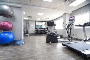 Un gimnasio con cintas de correr, elípticas y pelotas de ejercicio.