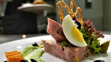 Un plat composé de différents aliments, notamment une tranche de viande, un œuf dur et quelques légumes verts.