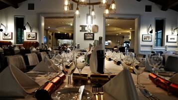 Zona pranzo con tavoli apparecchiati per un pasto, calici da vino, posate e una bottiglia di vino.