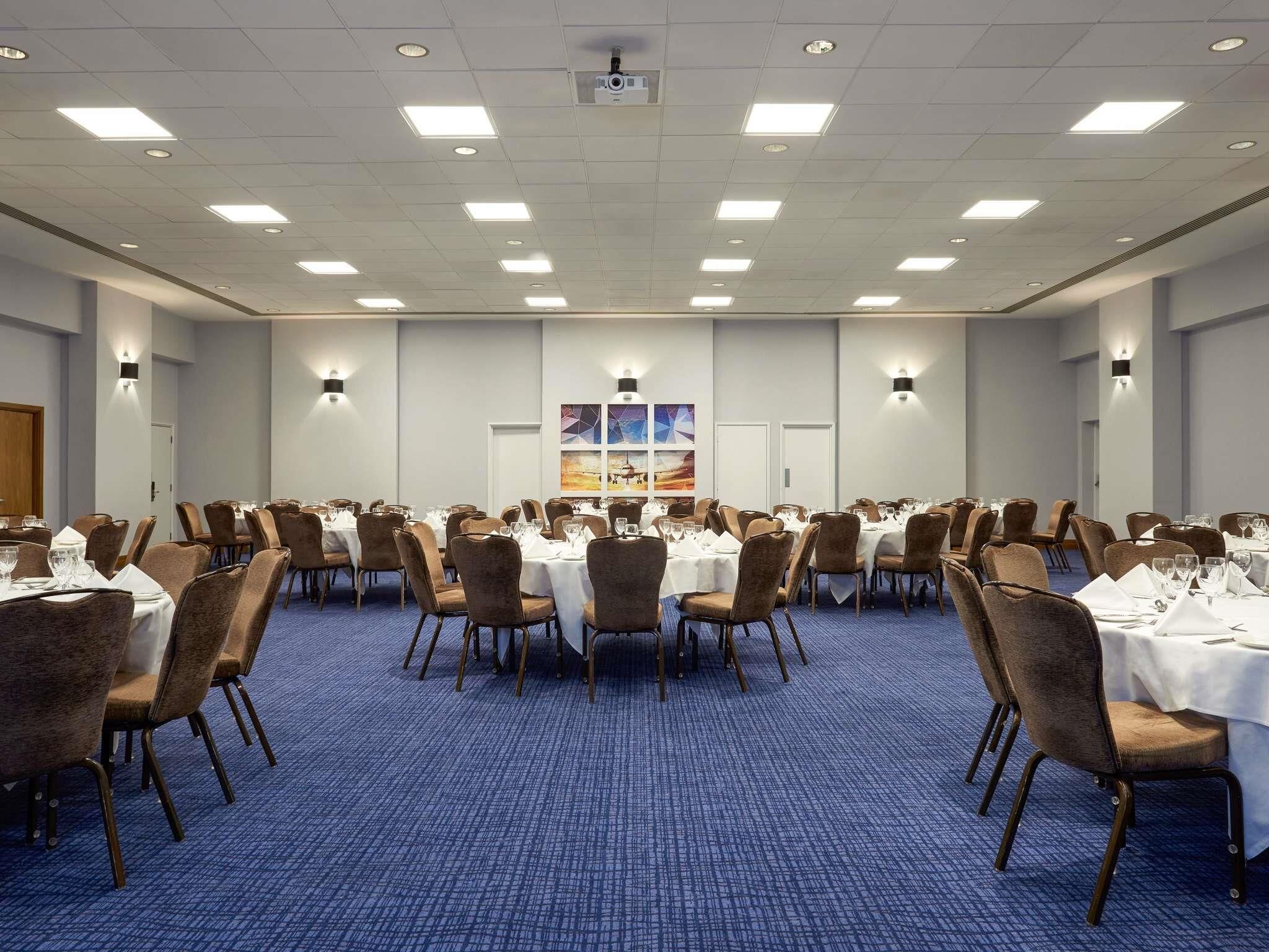 A conference room with round tables, chairs, and a carpeted floor.