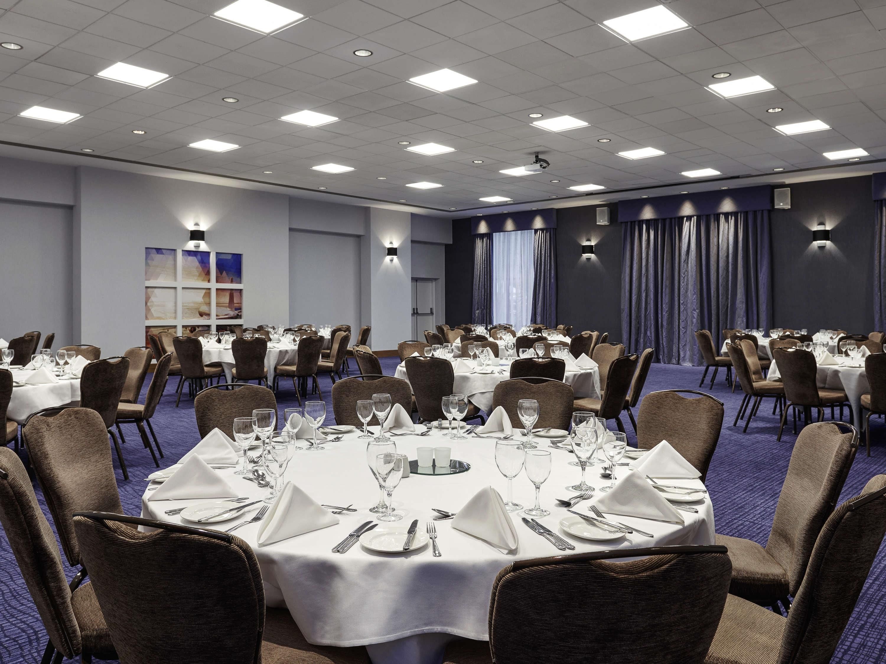 A banquet hall with round tables set for dining, equipped with chairs and table settings.
