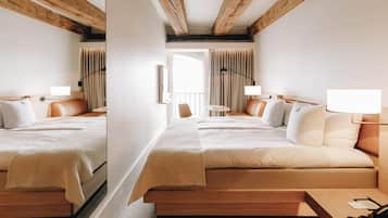 A hotel room with a large bed, a desk, and a chair. There is a window with curtains, a lamp, and a phone on the desk.