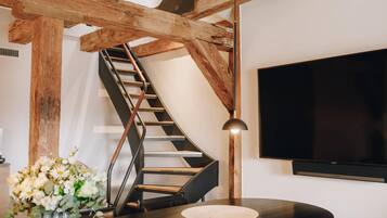 A modern interior with a curved staircase, a flat-screen TV, and a minimalist dining area.