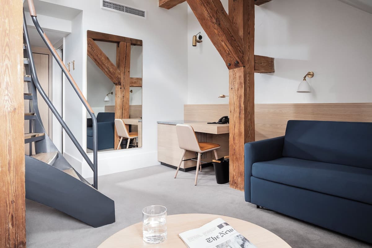 Uma sala de estar moderna com um sofá azul, uma escrivaninha de madeira e uma escada.