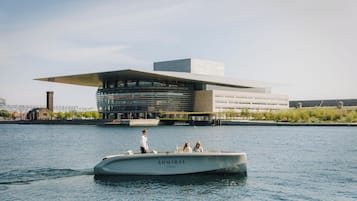 A boat named 'ADMIRAL Hotel' on water with a modern building in the background.