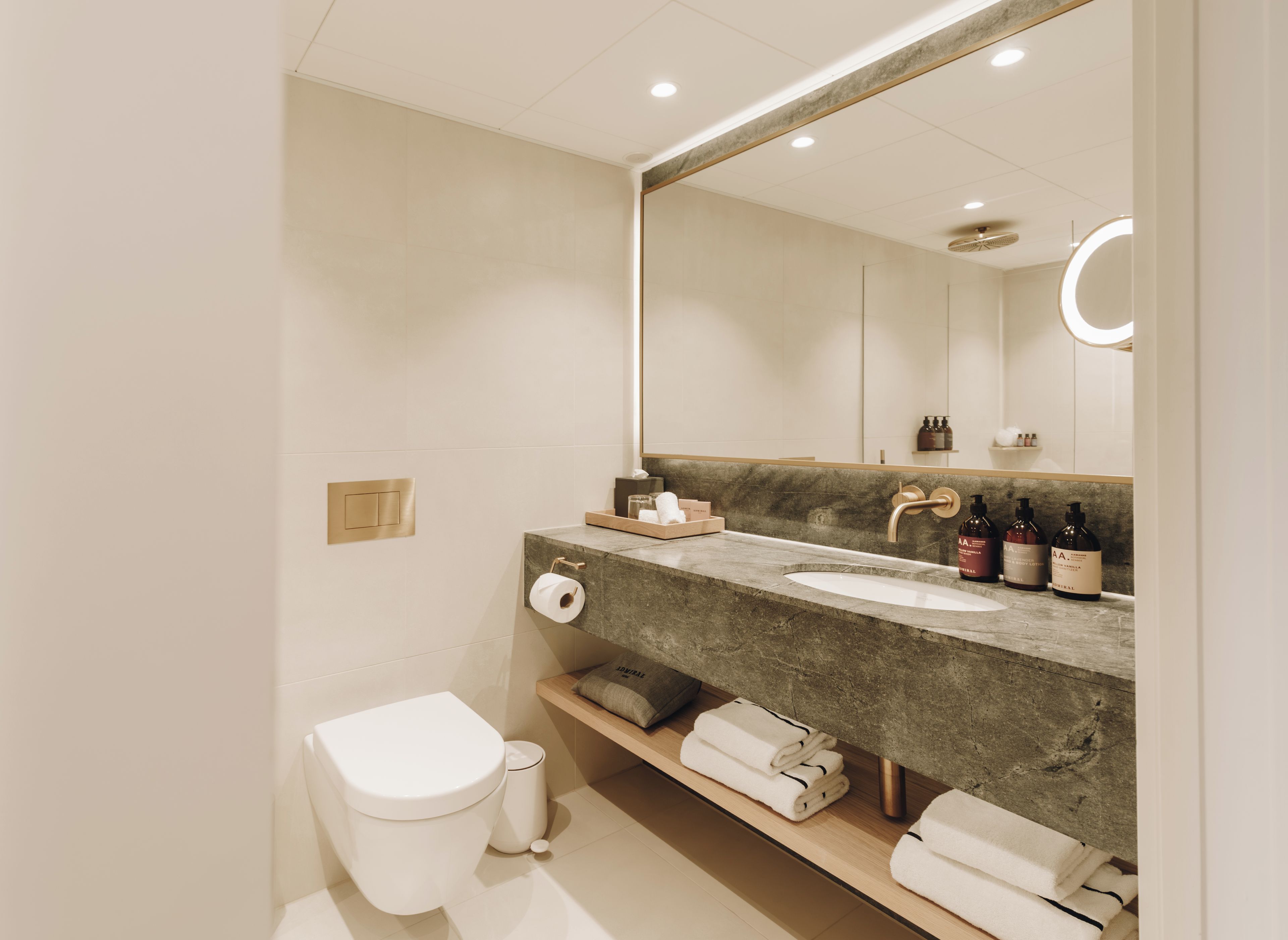 A modern bathroom with a marble sink, a toilet, and a large mirror.