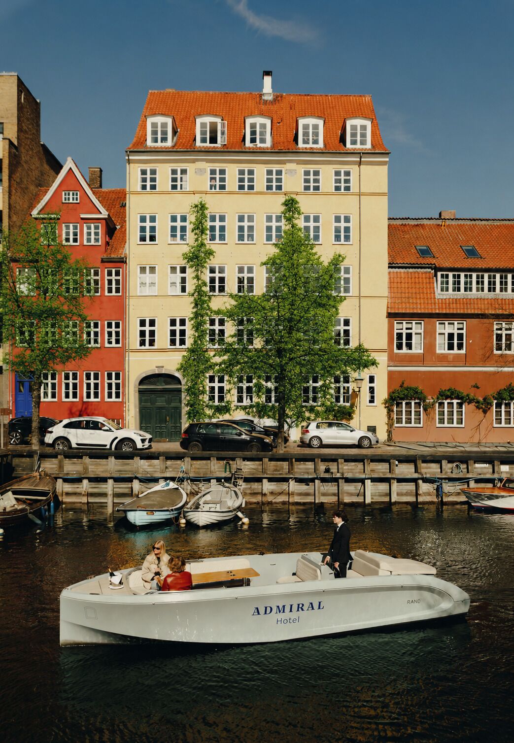 A boat named 'Admiral' docked at a marina with a building in the background.