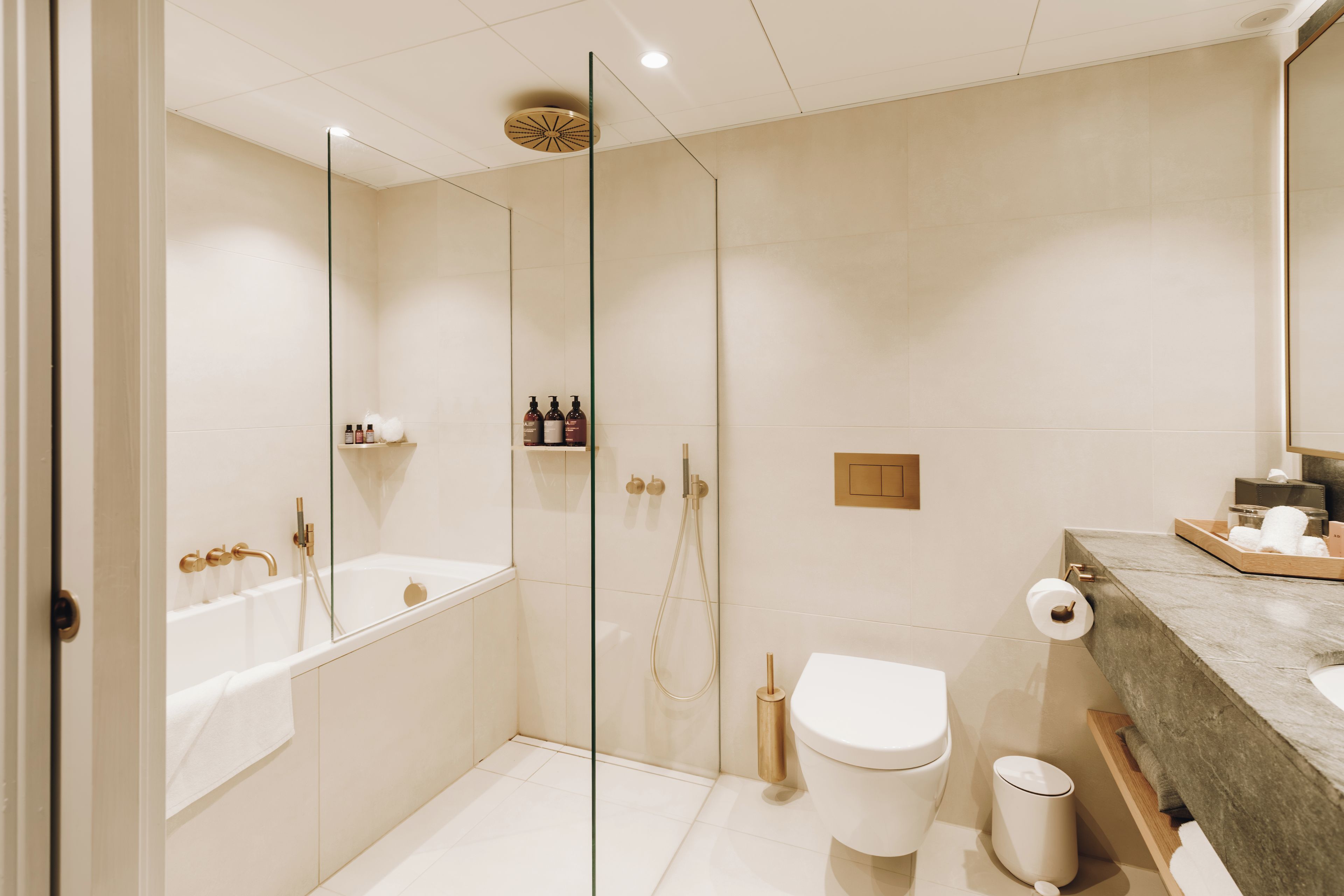 A modern bathroom with a glass-enclosed shower, a bathtub, and a toilet.