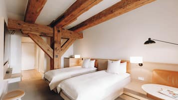 Habitación de hotel con dos camas, vigas de madera, un escritorio y una silla.