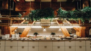Un buffet avec plusieurs points de service, des poutres en bois et des plantes suspendues.