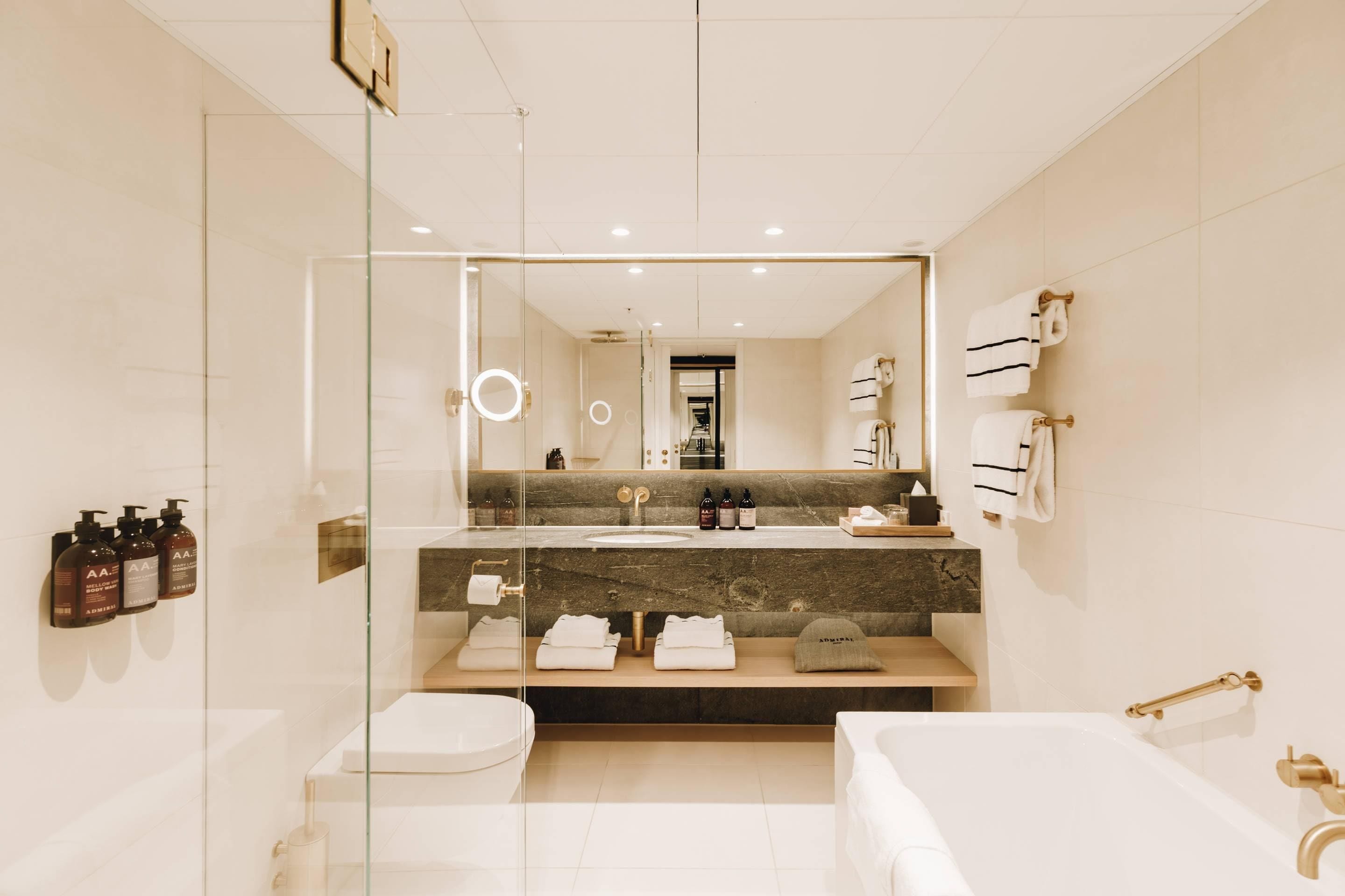 Een moderne badkamer met een douchecabine van glas, een wastafel met een marmeren aanrechtblad en een bad.