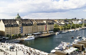 Ein historisches Gebäude mit einer markanten Kuppel, eine Marina mit verschiedenen Booten und eine Uferpromenade.