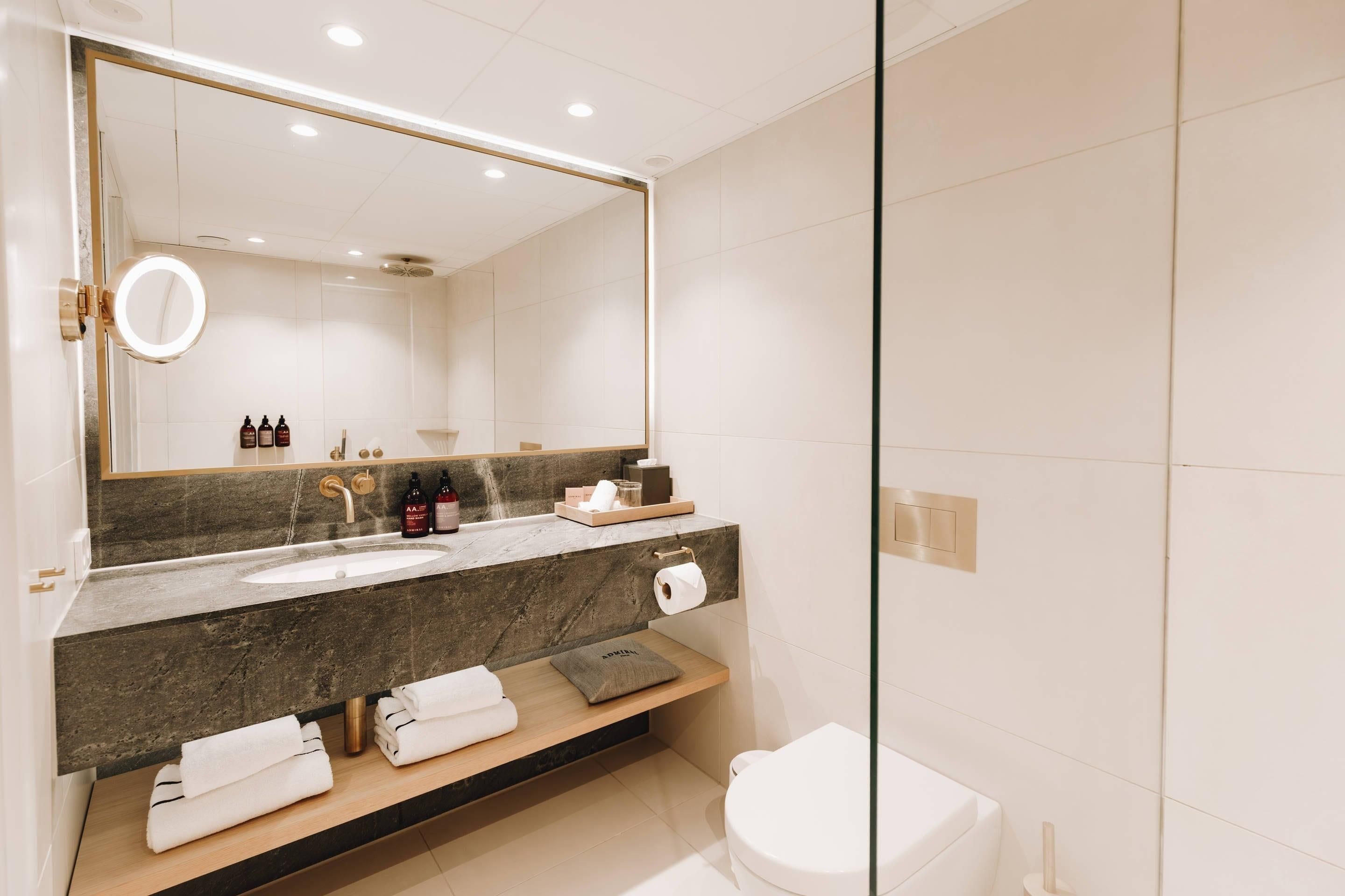 Un baño moderno con un espejo grande, un lavabo y un inodoro.