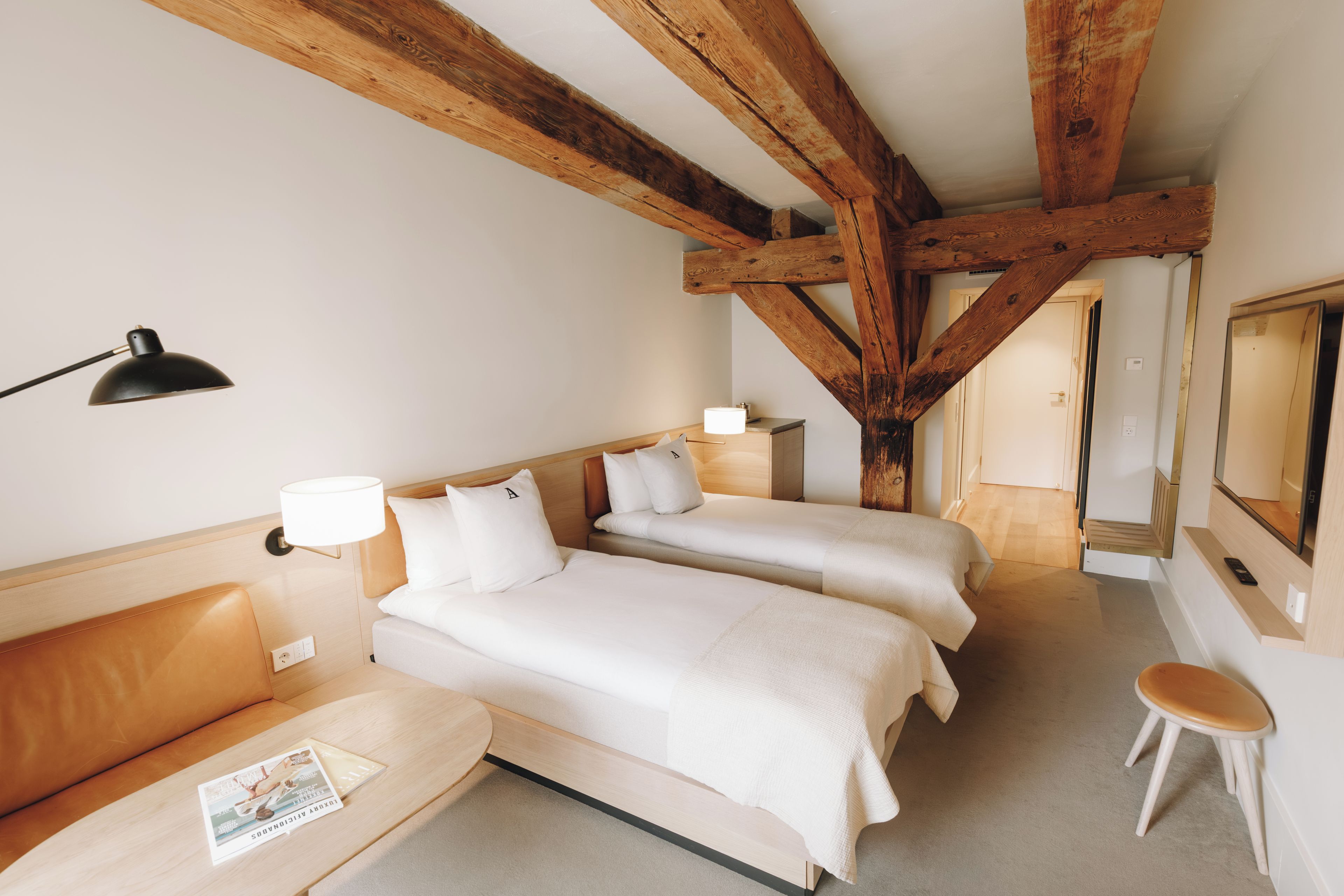 Habitación de hotel con dos camas, un sofá, una mesita y un espejo.